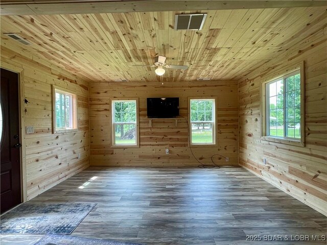 unfurnished room with wood ceiling, plenty of natural light, wood walls, a ceiling fan, and wood finished floors