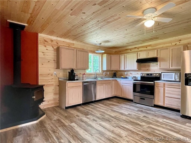 kitchen with stainless steel appliances, wood ceiling, a wood stove, light brown cabinetry, and under cabinet range hood