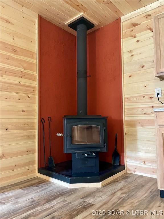 detailed view of wood finished floors, a wood stove, wood ceiling, and wooden walls