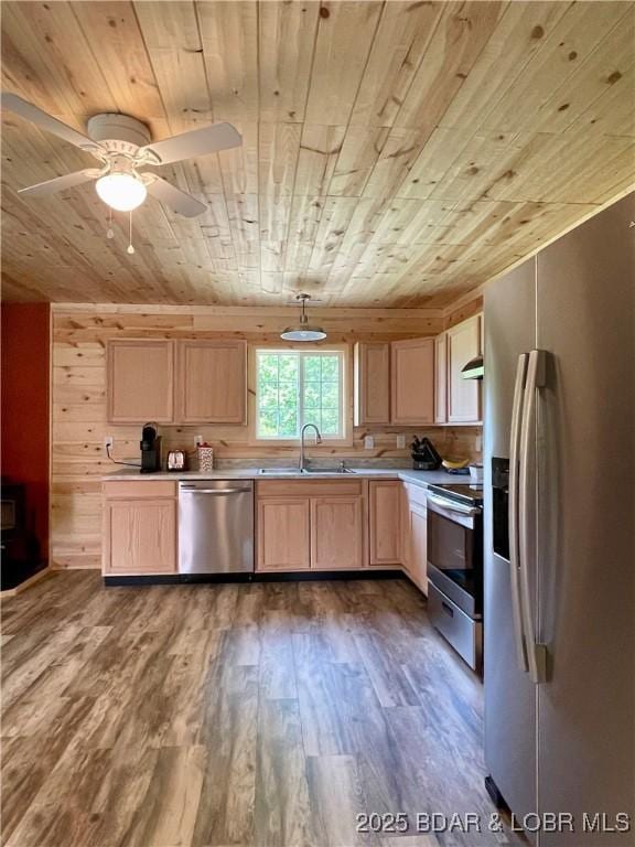 kitchen featuring stainless steel appliances, wood ceiling, a sink, light brown cabinets, and wood finished floors
