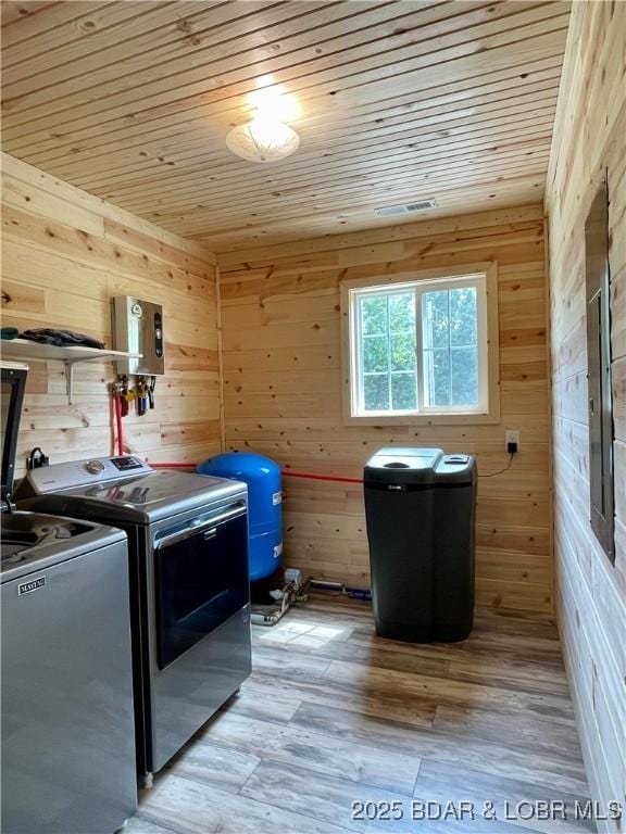 laundry room featuring wooden ceiling, wooden walls, washer and clothes dryer, and light wood-style floors