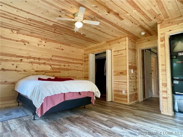 bedroom featuring wood ceiling, wood walls, wood finished floors, and a ceiling fan