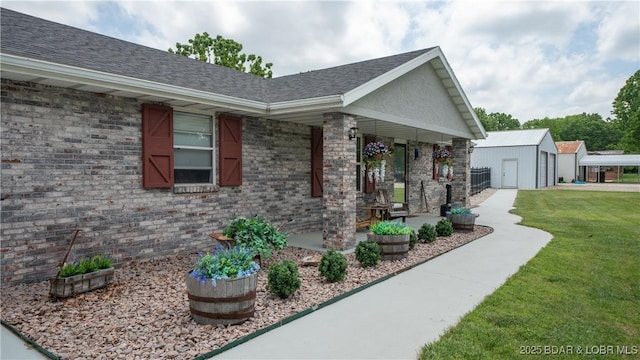 312 Charger Dr, Macks Creek, MO 65786 - view of home's exterior featuring covered porch, a lawn, an outbuilding, and brick siding