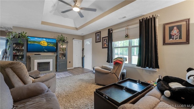 312 Charger Dr, Macks Creek, MO 65786 - living room with ceiling fan, a glass covered fireplace, a tray ceiling, and baseboards