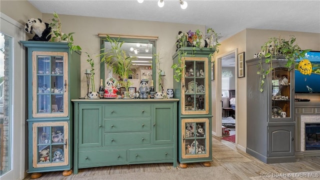 312 Charger Dr, Macks Creek, MO 65786 - bar with plenty of natural light, light wood finished floors, a glass covered fireplace, and a textured ceiling