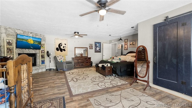 312 Charger Dr, Macks Creek, MO 65786 - bedroom featuring wood finished floors, a textured ceiling, baseboards, a fireplace, and a ceiling fan