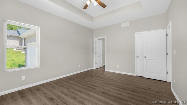 103 Primrose Ln, Camdenton, MO 65020 - unfurnished bedroom featuring dark wood finished floors, baseboards, a raised ceiling, and a ceiling fan