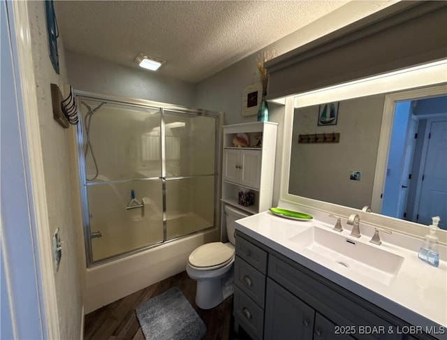1089 Buckingham Dr Unit 1, Camdenton, MO 65020 - bathroom featuring a textured ceiling, wood finished floors, bath / shower combo with glass door, toilet, and vanity