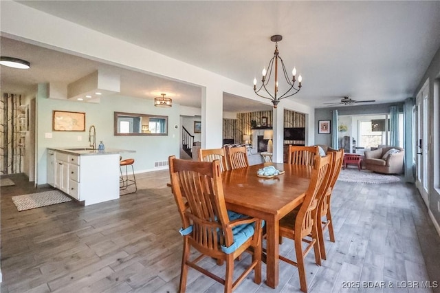 138 Siesta Cir, Camdenton, MO 65020 - dining room featuring ceiling fan, dark wood-style floors, a chandelier, stairs, and baseboards