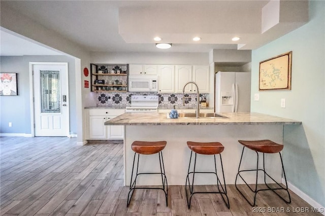 138 Siesta Cir, Camdenton, MO 65020 - kitchen with white appliances, a sink, a breakfast bar area, white cabinets, and recessed lighting