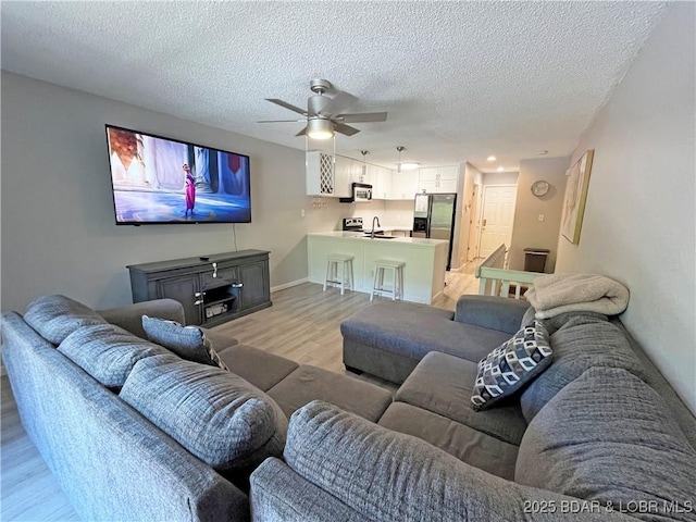 1130 Rachel Rd Unit 108, Osage Beach, MO 65065 - living area featuring light wood-style flooring, a ceiling fan, a textured ceiling, and baseboards