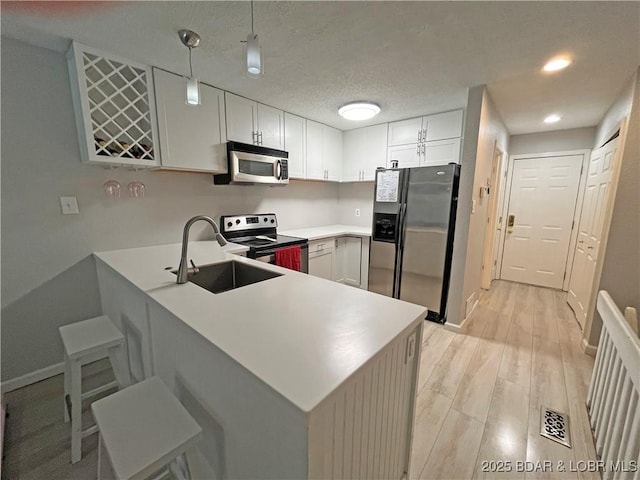 1130 Rachel Rd Unit 108, Osage Beach, MO 65065 - kitchen with stainless steel appliances, a sink, a peninsula, light wood-type flooring, and baseboards