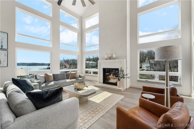 154 Via Cresta Dr, Sunrise Beach, MO 65079 - living room with a high ceiling, a water view, a glass covered fireplace, light wood-type flooring, and a ceiling fan