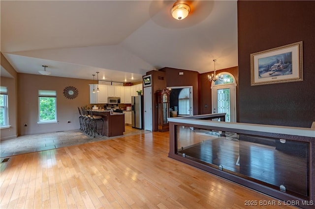 179 Regency Cove Dr, Lake Ozark, MO 65049 - kitchen with stainless steel appliances, a chandelier, light wood finished floors, white cabinets, and vaulted ceiling