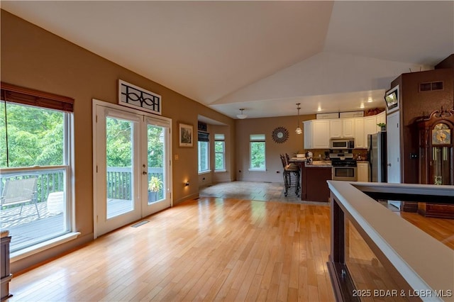 179 Regency Cove Dr, Lake Ozark, MO 65049 - kitchen featuring stainless steel appliances, vaulted ceiling, white cabinetry, decorative light fixtures, and light wood-style flooring
