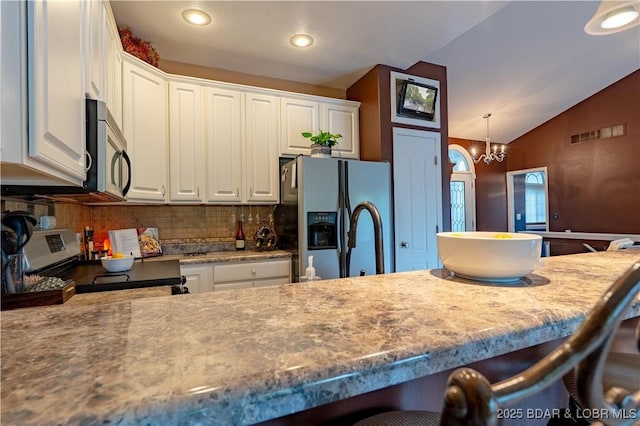 179 Regency Cove Dr, Lake Ozark, MO 65049 - kitchen with stainless steel appliances, a breakfast bar, vaulted ceiling, white cabinetry, and decorative backsplash