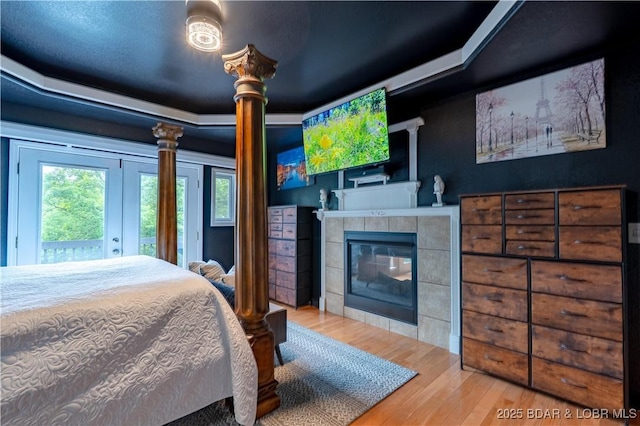 179 Regency Cove Dr, Lake Ozark, MO 65049 - bedroom with wood finished floors, a tiled fireplace, access to exterior, and decorative columns