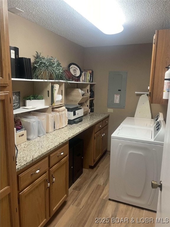 821 Winn Rd Unit 10D, Osage Beach, MO 65065 - laundry area featuring electric panel, cabinet space, washing machine and dryer, light wood-type flooring, and a textured ceiling