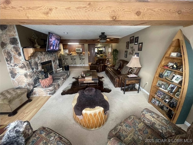 821 Winn Rd Unit 10D, Osage Beach, MO 65065 - carpeted living room with a stone fireplace, ceiling fan, and beam ceiling