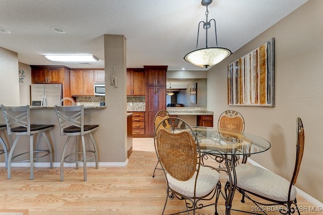 821 Winn Rd Unit 10D, Osage Beach, MO 65065 - dining area with light wood-style flooring, a textured ceiling, and baseboards