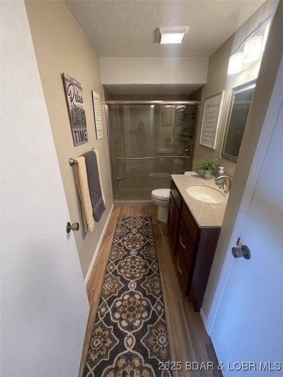 821 Winn Rd Unit 10D, Osage Beach, MO 65065 - full bath with a textured ceiling, vanity, a stall shower, wood finished floors, and toilet