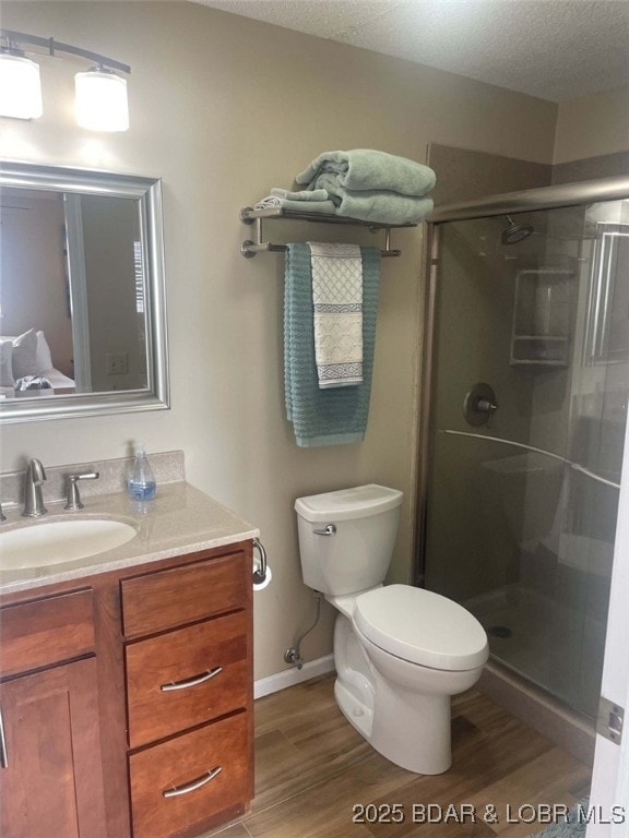 821 Winn Rd Unit 10D, Osage Beach, MO 65065 - bathroom featuring wood finished floors, vanity, a stall shower, toilet, and baseboards