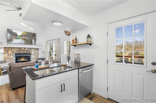 855 Ginger Rd, Lake Ozark, MO 65049 - kitchen with dishwasher, a sink, dark stone counters, white cabinetry, and a stone fireplace