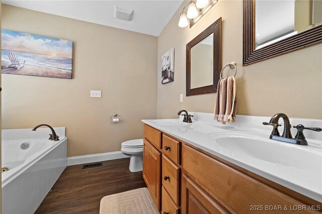 790 College Blvd, Osage Beach, MO 65065 - bathroom with baseboards, double vanity, wood finished floors, a garden tub, and toilet