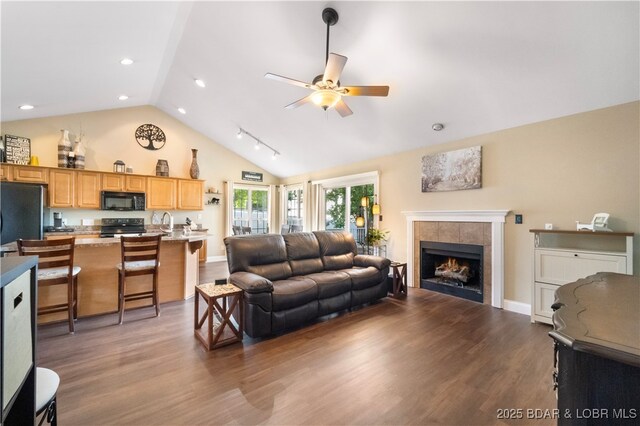 790 College Blvd, Osage Beach, MO 65065 - living area featuring ceiling fan, dark wood-style flooring, a tile fireplace, high vaulted ceiling, and baseboards