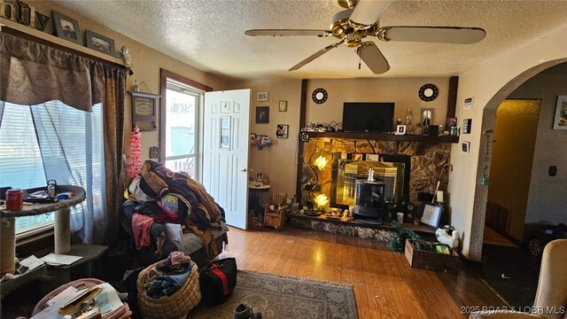 1501 Long Ln, Eldon, MO 65026 - living area featuring a wood stove, arched walkways, a textured ceiling, a ceiling fan, and wood finished floors