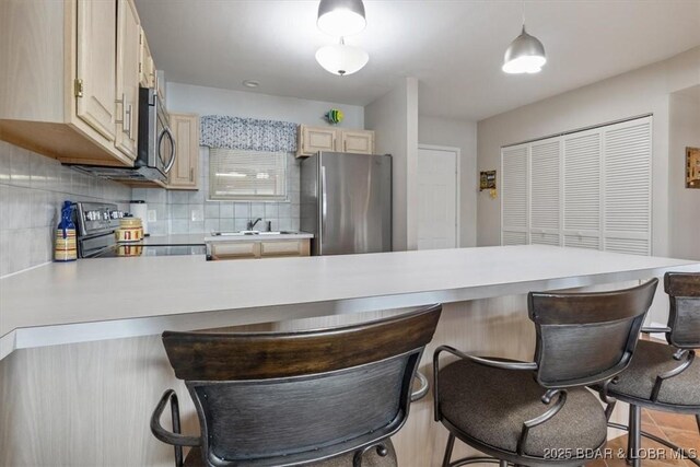 90 Falls Point Dr Unit 2C, Lake Ozark, MO 65049 - kitchen featuring appliances with stainless steel finishes, a peninsula, backsplash, and light countertops
