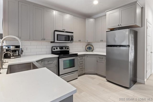166 Oak Harbor Dr Unit 3D, Camdenton, MO 65020 - kitchen featuring appliances with stainless steel finishes, gray cabinets, a sink, tasteful backsplash, and light countertops