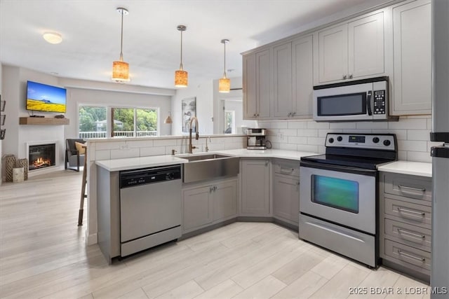 166 Oak Harbor Dr Unit 3D, Camdenton, MO 65020 - kitchen featuring stainless steel appliances, gray cabinets, a sink, a peninsula, and open floor plan