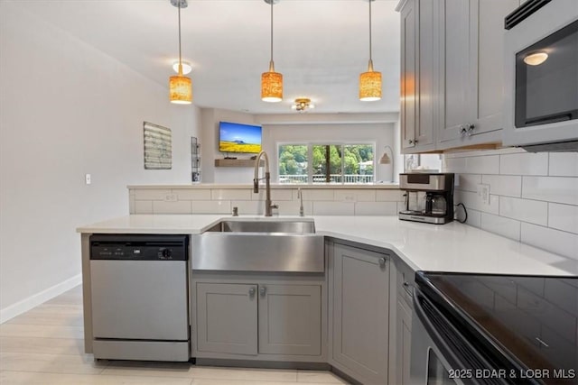 166 Oak Harbor Dr Unit 3D, Camdenton, MO 65020 - kitchen featuring appliances with stainless steel finishes, gray cabinets, a sink, backsplash, and a peninsula