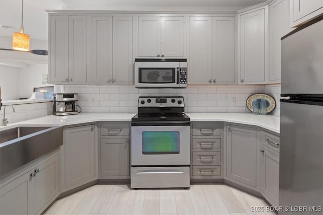 166 Oak Harbor Dr Unit 3D, Camdenton, MO 65020 - kitchen with appliances with stainless steel finishes, gray cabinetry, light countertops, and decorative backsplash