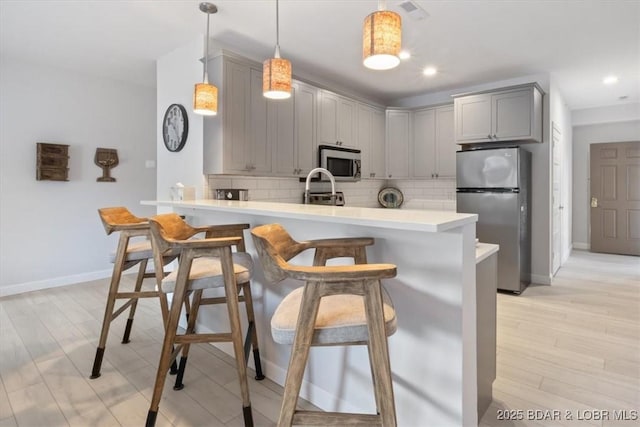 166 Oak Harbor Dr Unit 3D, Camdenton, MO 65020 - kitchen with appliances with stainless steel finishes, gray cabinetry, a peninsula, backsplash, and light countertops