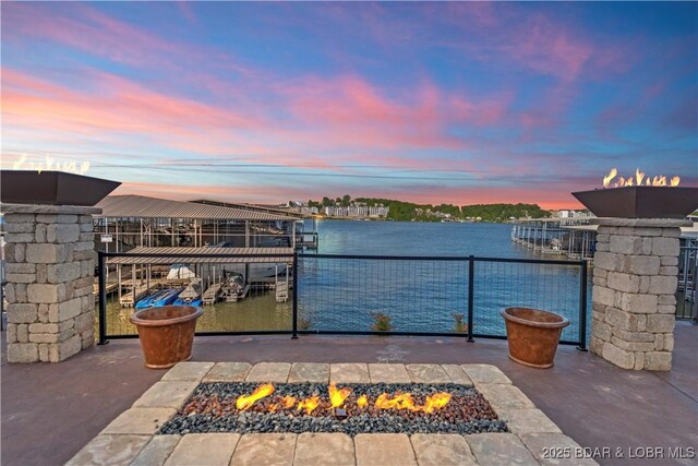 1184 Jeffries Rd Unit 310, Osage Beach, MO 65065 - patio terrace at dusk with an outdoor fire pit, a boat dock, a water view, and boat lift