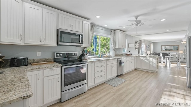 2195 Valley Rd, Osage Beach, MO 65065 - kitchen featuring stainless steel appliances, ceiling fan, a sink, a peninsula, and white cabinetry