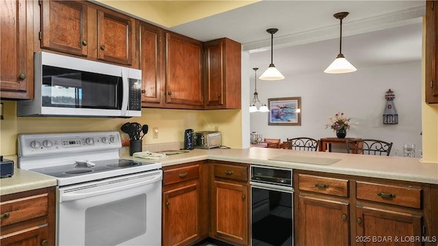 5940 Baydy Peak Rd Unit 325, Osage Beach, MO 65065 - kitchen featuring white appliances, light countertops, pendant lighting, a peninsula, and brown cabinetry