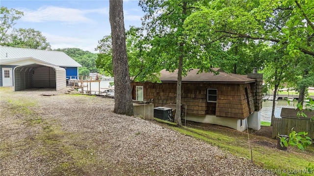 47 Dixie Ln, Sunrise Beach, MO 65079 - view of home's exterior featuring central AC unit, gravel driveway, and a water view