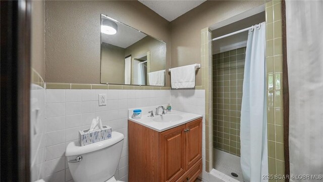 47 Dixie Ln, Sunrise Beach, MO 65079 - bathroom featuring tile walls, vanity, toilet, a stall shower, and a textured wall