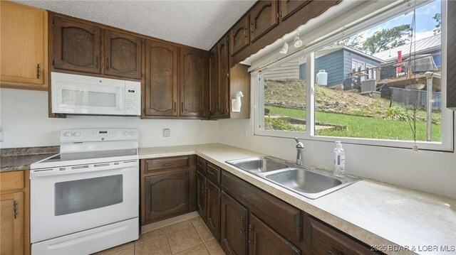 47 Dixie Ln, Sunrise Beach, MO 65079 - kitchen with white appliances, a sink, light tile patterned flooring, a textured ceiling, and light countertops