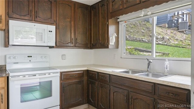 47 Dixie Ln, Sunrise Beach, MO 65079 - kitchen featuring white appliances, a sink, light countertops, and dark brown cabinets
