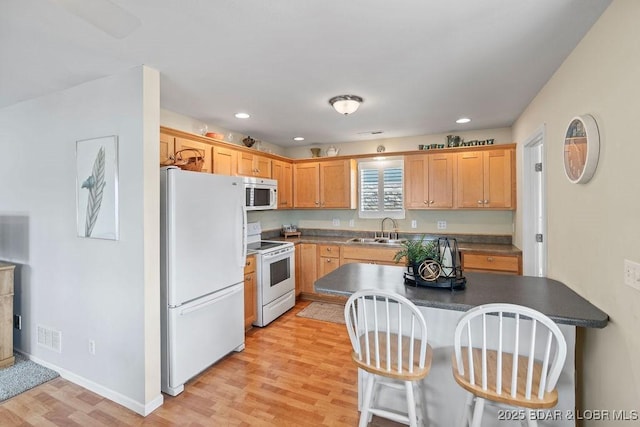 29566 Hunter Rd, Gravois Mills, MO 65037 - kitchen with white appliances, a sink, light wood-style flooring, dark countertops, and a kitchen breakfast bar