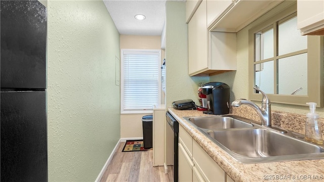 86 Henrys Way Unit 2A, Linn Creek, MO 65052 - kitchen featuring a sink, a textured wall, light wood finished floors, white cabinetry, and light countertops
