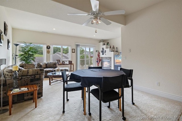 879 Great Ship St, Osage Beach, MO 65065 - dining space with light carpet, a glass covered fireplace, ceiling fan, and baseboards