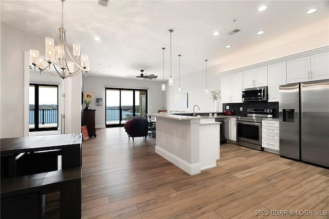 166 Captiva Dr Unit 8B, Sunrise Beach, MO 65079 - kitchen featuring appliances with stainless steel finishes, recessed lighting, light wood finished floors, open floor plan, and backsplash