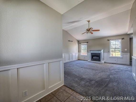 20715 Hiltner Ln, Saint Robert, MO 65584 - unfurnished living room featuring carpet, a ceiling fan, a fireplace with raised hearth, tile patterned floors, and wainscoting