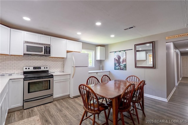 30734 Ottersway Rd, Gravois Mills, MO 65037 - kitchen with appliances with stainless steel finishes, light wood-type flooring, backsplash, white cabinets, and recessed lighting