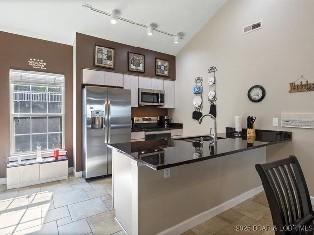 335 Charleston Dr Unit 3B, Lake Ozark, MO 65049 - kitchen featuring appliances with stainless steel finishes, a peninsula, a sink, dark countertops, and white cabinets